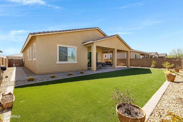 rear view of house with a fenced backyard, stucco siding, a tiled roof, and a patio
