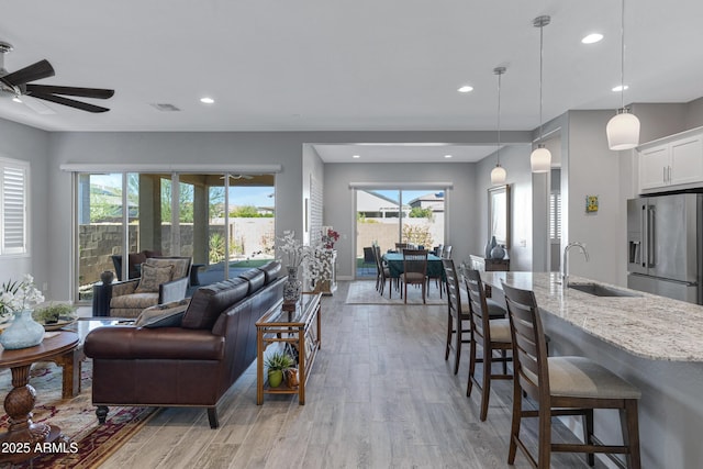 living area with recessed lighting, light wood-style floors, and ceiling fan