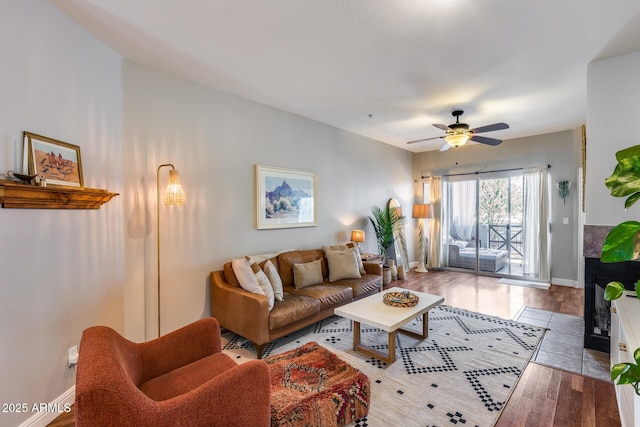 living area featuring a ceiling fan, wood finished floors, and baseboards