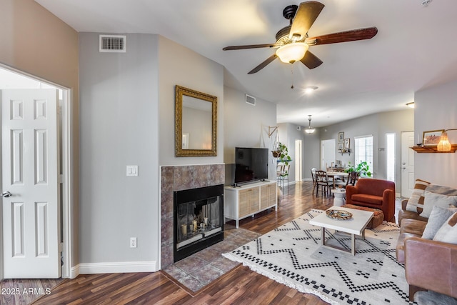 living area featuring dark wood-type flooring, baseboards, visible vents, and a tile fireplace