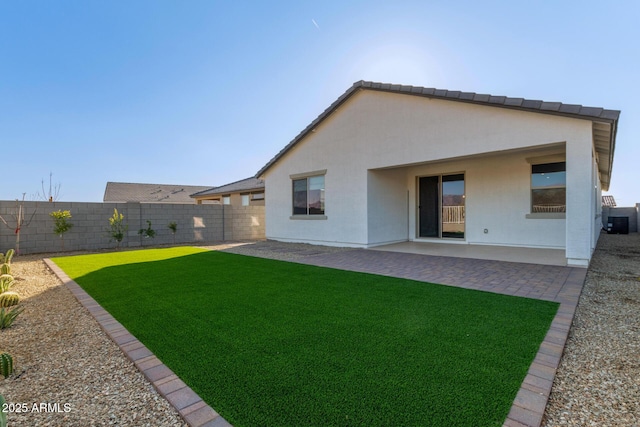 back of property with a yard and a patio