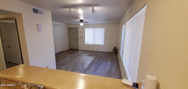 empty room featuring ceiling fan, dark hardwood / wood-style flooring, and track lighting