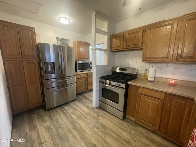 kitchen featuring backsplash, stainless steel appliances, light hardwood / wood-style floors, and ceiling fan