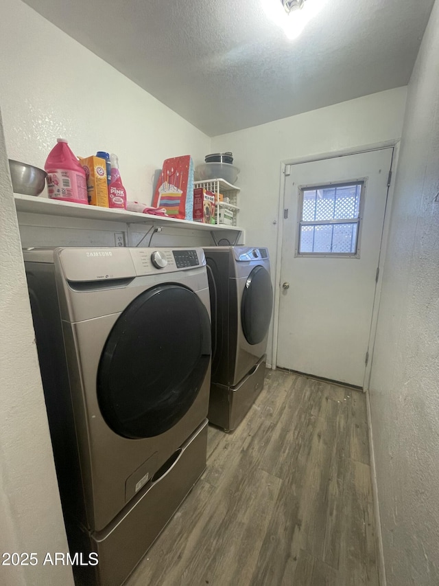 clothes washing area featuring washing machine and clothes dryer, hardwood / wood-style floors, and a textured ceiling