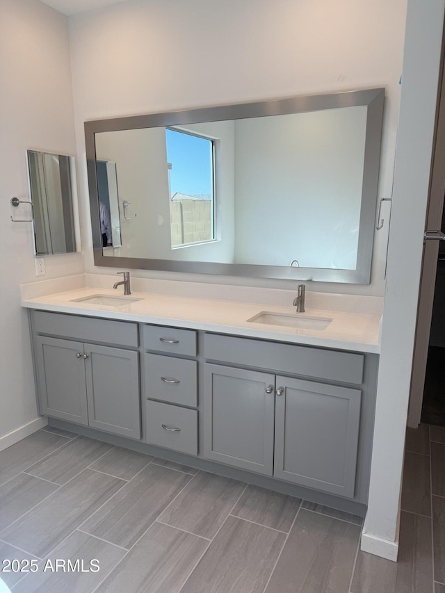 full bathroom featuring baseboards, double vanity, a sink, and wood tiled floor