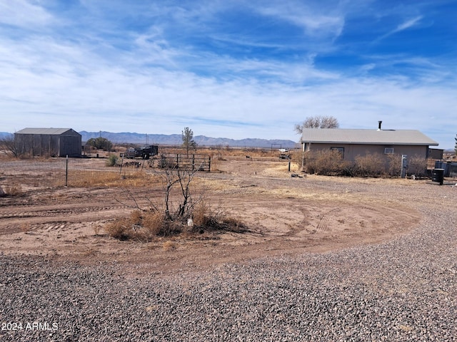 view of yard featuring a rural view, a mountain view, and fence