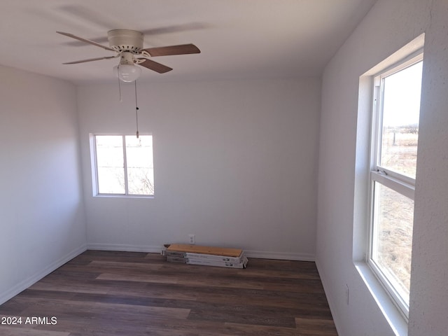 spare room featuring baseboards, dark wood finished floors, and a ceiling fan
