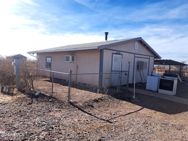 view of outdoor structure featuring a wall mounted air conditioner and fence