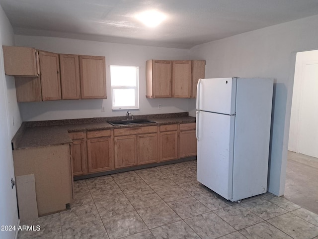 kitchen with freestanding refrigerator, a sink, and dark countertops