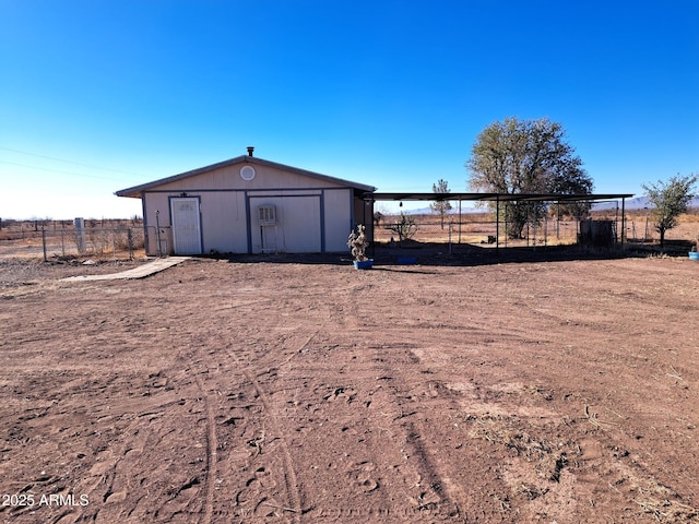view of outdoor structure featuring a rural view, fence, and an outdoor structure