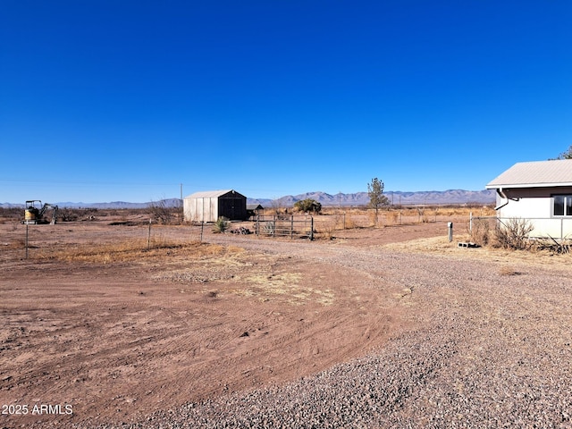 view of yard with an outbuilding, a rural view, a mountain view, an outdoor structure, and fence