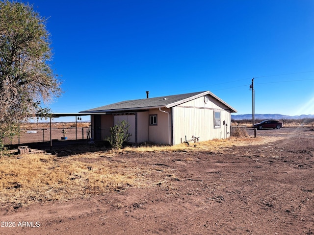 view of outdoor structure with fence, a mountain view, and a carport