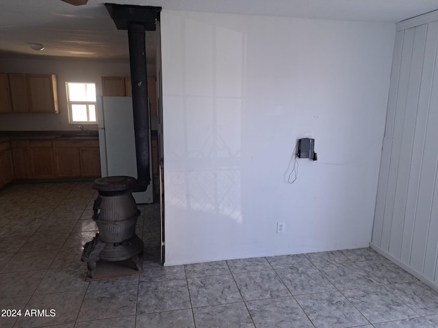 interior space featuring a wood stove, light tile patterned floors, and a sink