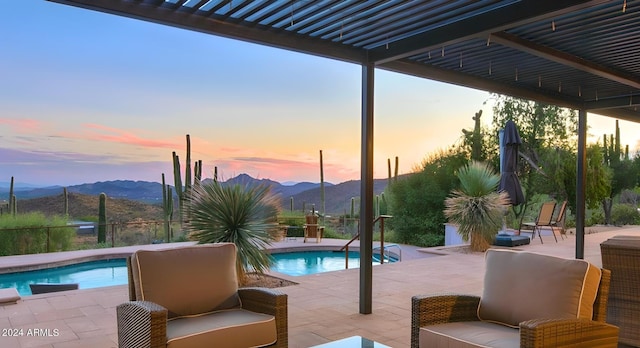 pool at dusk with a patio, an outdoor pool, and a mountain view