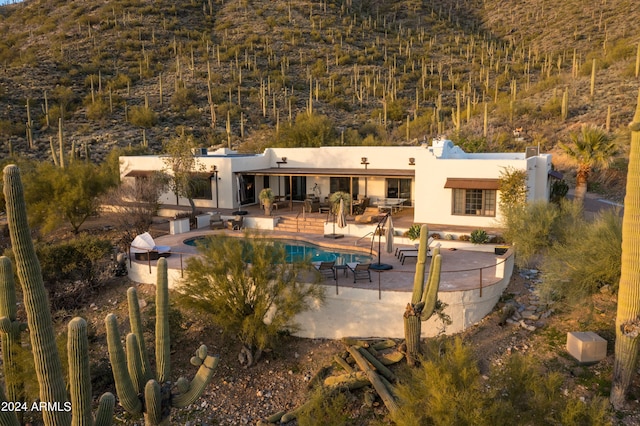 back of property with a patio area, an outdoor pool, and stucco siding