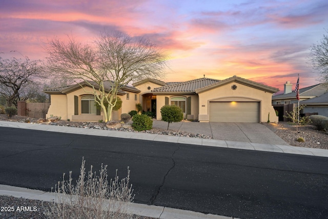 mediterranean / spanish-style home featuring concrete driveway, an attached garage, a tile roof, and stucco siding