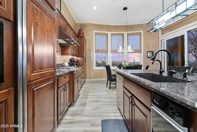 kitchen with ornamental molding, pendant lighting, a sink, and under cabinet range hood