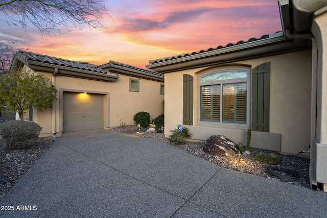 view of front of house featuring stucco siding, an attached garage, driveway, and a tiled roof