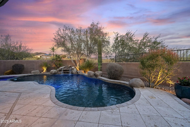 pool at dusk featuring a patio area, a fenced backyard, and a fenced in pool