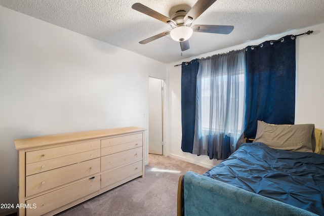 bedroom featuring ceiling fan, light carpet, and a textured ceiling