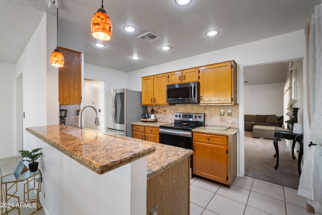 kitchen featuring hanging light fixtures, kitchen peninsula, a breakfast bar, appliances with stainless steel finishes, and a textured ceiling