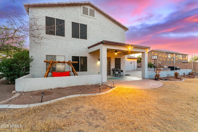 back house at dusk featuring a patio and ceiling fan