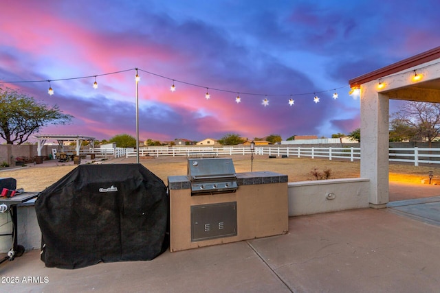 patio terrace at dusk featuring a grill and area for grilling