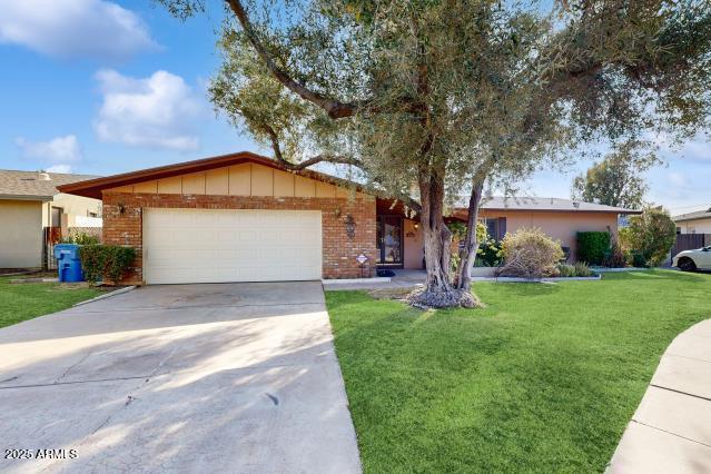 ranch-style house with a garage and a front lawn