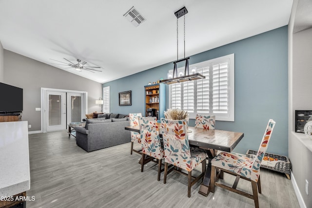 dining area featuring french doors, light hardwood / wood-style flooring, ceiling fan with notable chandelier, and vaulted ceiling