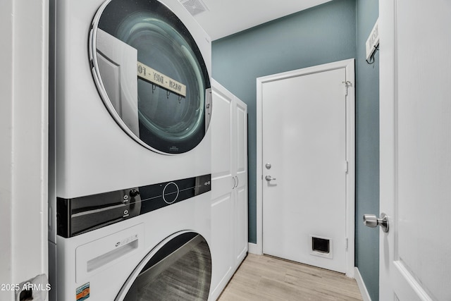 laundry room featuring stacked washer / drying machine and light hardwood / wood-style flooring