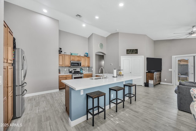 kitchen with backsplash, a large island with sink, sink, a kitchen bar, and stainless steel appliances