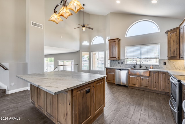 kitchen with a kitchen island, dark hardwood / wood-style flooring, ceiling fan, stainless steel appliances, and high vaulted ceiling