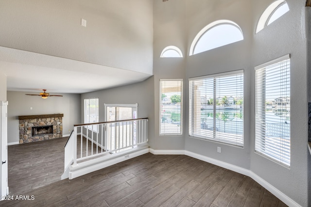 unfurnished room featuring a stone fireplace, dark hardwood / wood-style floors, and a wealth of natural light