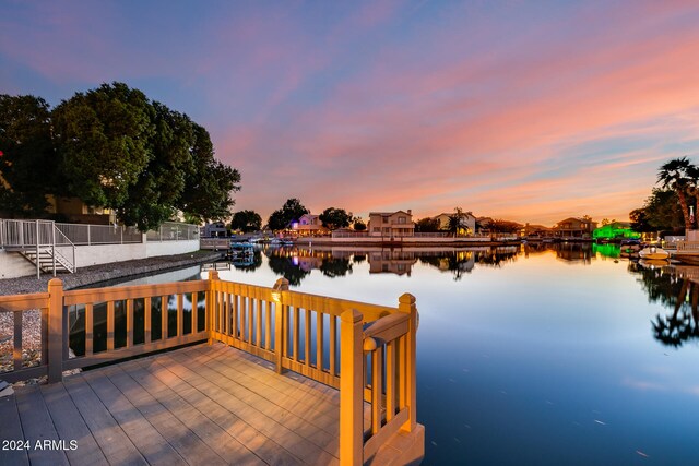 deck at dusk featuring a water view