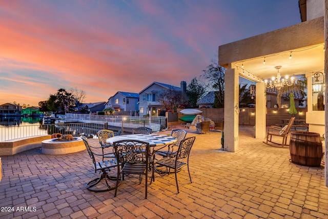 patio terrace at dusk with an outdoor fire pit and a water view