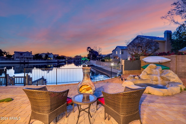 pool at dusk featuring a patio area and a water view