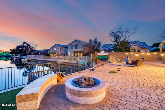 patio terrace at dusk with a water view and a fire pit