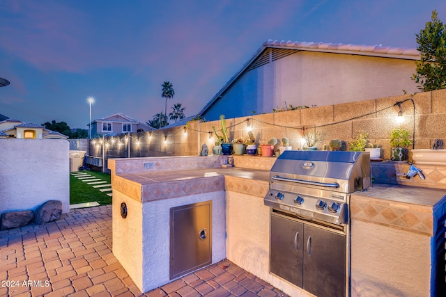 patio terrace at dusk featuring an outdoor kitchen and grilling area