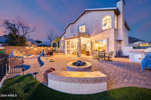 back house at dusk featuring a patio area and an outdoor fire pit