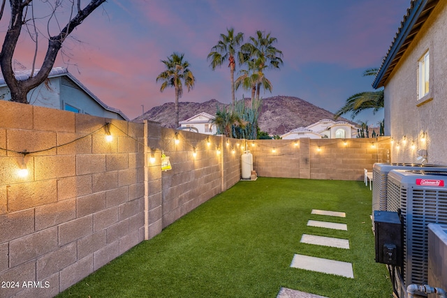 yard at dusk with a mountain view and central AC unit