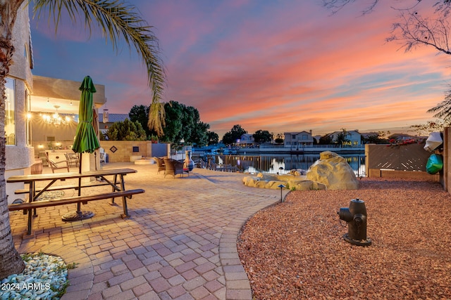 yard at dusk with a patio and a water view