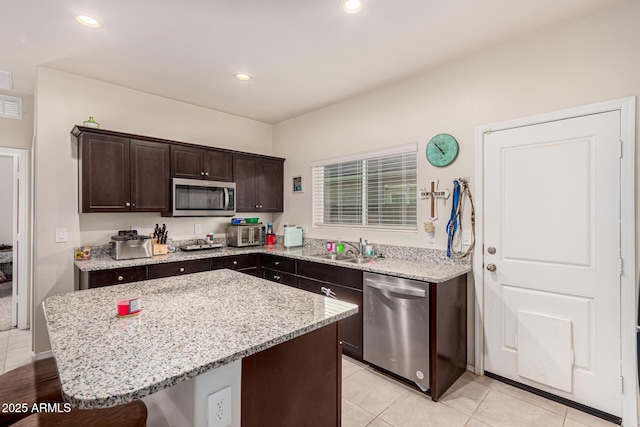 kitchen with a breakfast bar, sink, a center island, dark brown cabinets, and appliances with stainless steel finishes