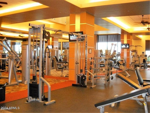 workout area with a tray ceiling and ceiling fan