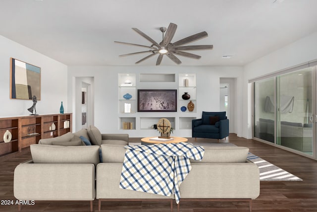 living room featuring built in shelves, dark hardwood / wood-style floors, and ceiling fan