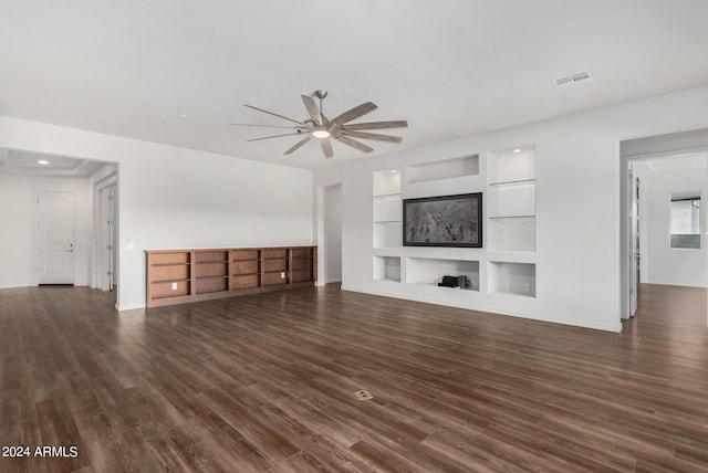 unfurnished living room featuring ceiling fan, built in features, and dark hardwood / wood-style floors