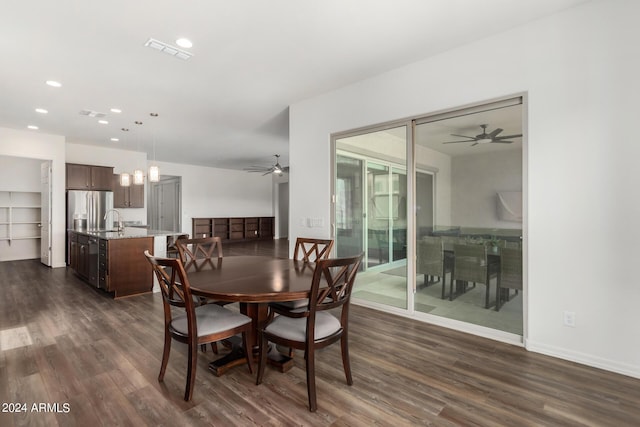 dining area featuring sink, dark wood-type flooring, and ceiling fan with notable chandelier