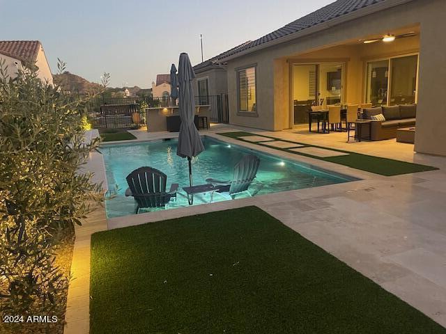 pool at dusk with outdoor lounge area and a patio area