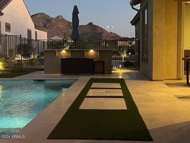 pool at dusk with a patio area and a mountain view