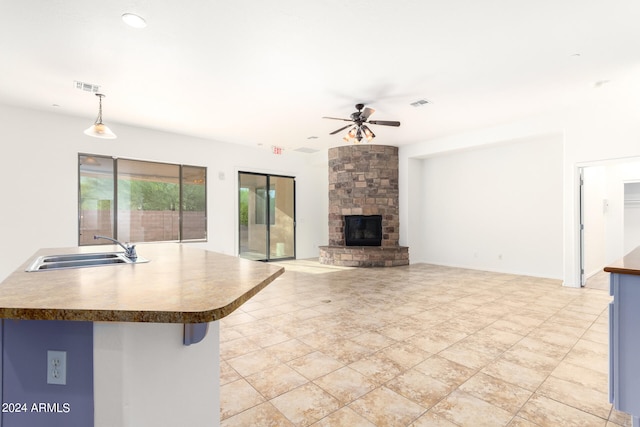 kitchen with a fireplace, sink, ceiling fan, and decorative light fixtures