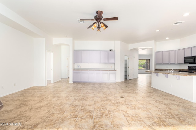 unfurnished living room featuring ceiling fan and sink